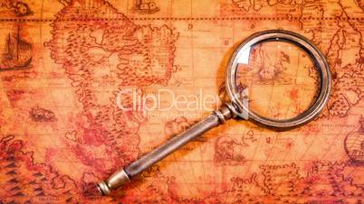 Vintage magnifying glass lying on ancient world map in 1565.