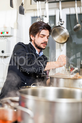 Chef stirring a huge pot of stew or casserole