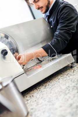 Commercial cook or chef slicing cold meat