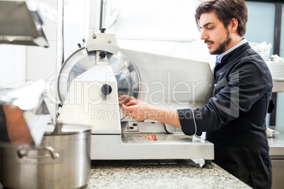 Commercial cook or chef slicing cold meat