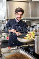 Chef cooking a vegetables stir fry over a hob