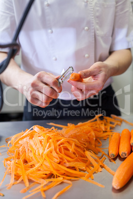 Chef in uniform preparing fresh carrot batons