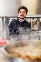 Chef cooking a vegetables stir fry over a hob