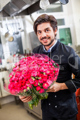Smiling chef holding bunches of fresh flowers