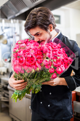 Smiling chef holding bunches of fresh flowers