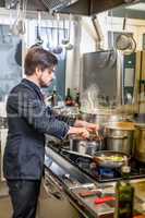 Chef cooking a vegetables stir fry over a hob