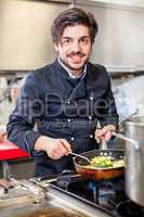 Chef cooking a vegetables stir fry over a hob