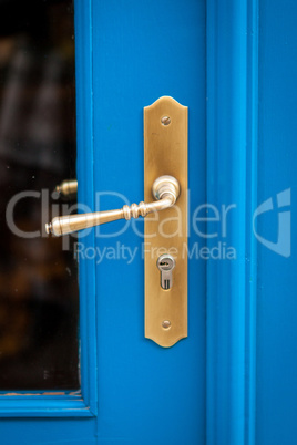 Brass door handle on a colorful blue door