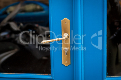 Brass door handle on a colorful blue door