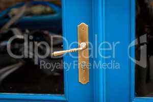 Brass door handle on a colorful blue door