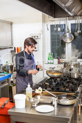 Chef cooking a vegetables stir fry over a hob
