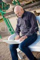 Man sitting on a bench using a laptop