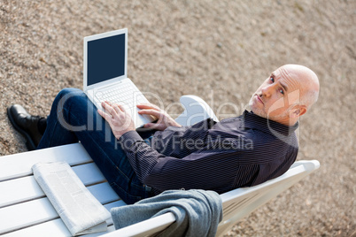 Man sitting on a bench using a laptop