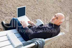 Man sitting on a bench using a laptop