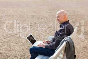 Man sitting on a bench using a laptop