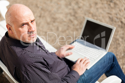 Man sitting on a bench using a laptop