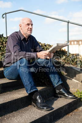 Man sitting on steps reading a newspaper