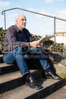 Man sitting on steps reading a newspaper