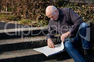 Man sitting on steps reading a newspaper