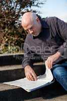 Man sitting on steps reading a newspaper