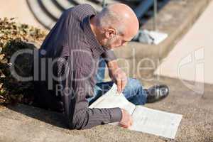 Man sitting on steps reading a newspaper