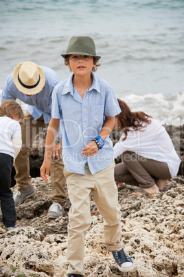 happy family sitting on rock and watching the ocean waves