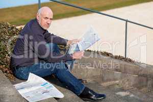 Man sitting on steps reading a newspaper