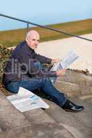 Man sitting on steps reading a newspaper