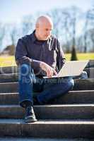 Man sitting on a bench using a laptop