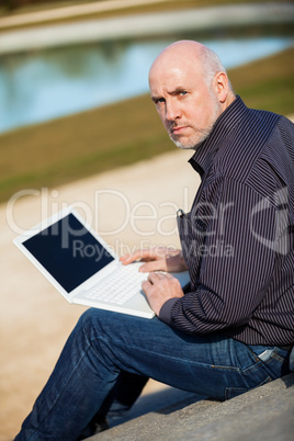 Man sitting on a bench using a laptop