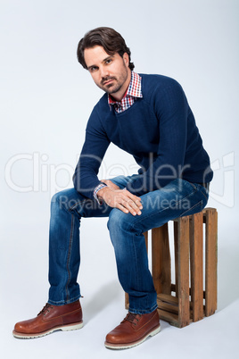 Handsome young man sitting on a wooden box