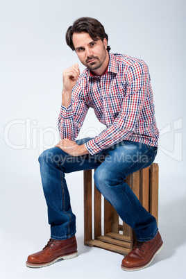 Handsome young man sitting on a wooden box