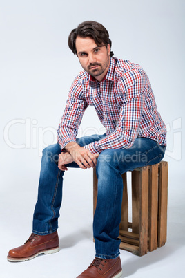 Handsome young man sitting on a wooden box