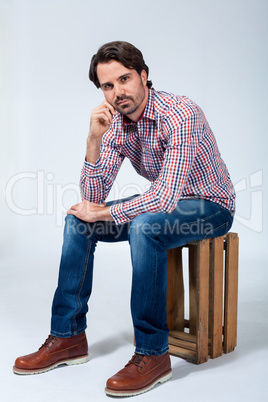 Handsome young man sitting on a wooden box