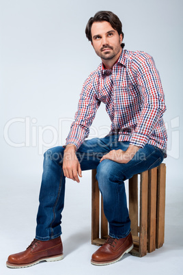 Handsome young man sitting on a wooden box