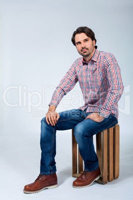 Handsome young man sitting on a wooden box