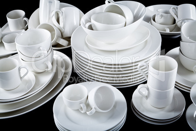 mixed white dishes cups and plates isolated on black