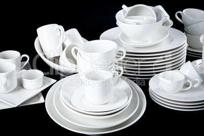 mixed white dishes cups and plates isolated on black