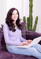 smiling woman on couch with notebook