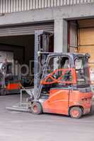 Small orange forklift parked at a warehouse