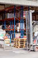 Small orange forklift parked at a warehouse