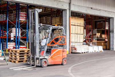 Small orange forklift parked at a warehouse