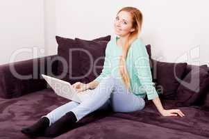 smiling woman on couch with notebook