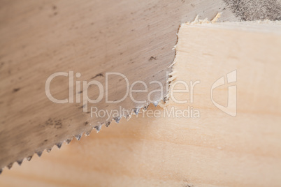 Hand saw cutting through a beam of wood