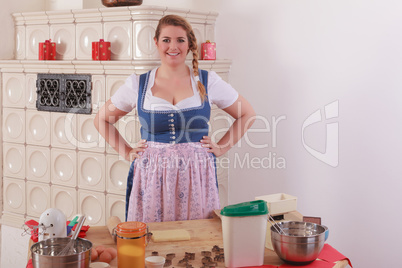 Bayerisches Mädchen im Dirndl vor einem Tisch mit Zutaten für das backen.