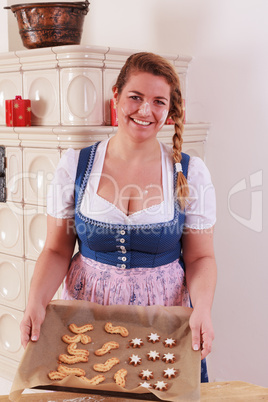 Junge Frau mit einem Kuchenblech voller Kekse und Mehl im Gesicht und auf der Brust