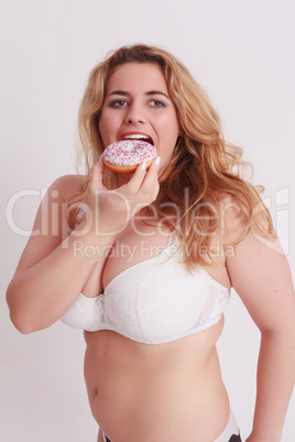 Frau mit großen Brüsten ißt einen bunten Muffin.