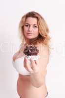 Frau mit großen Brüsten präsentiert einen Muffin aus Schokolade