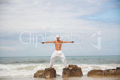 healthy man doing pilates yoga meditation on beach summer