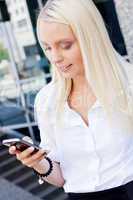 smiling attractive blonde businesswoman with smartphone